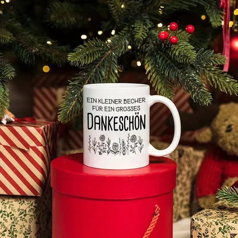 Eine hochwertige 11-Unzen-Keramik-Kaffeetasse mit stilvollem weißem Design, floralen Mustern und einem deutschen Dankesausdruck. Nur handwaschbar, geeignet für wiederholten Gebrauch und ein tolles Geschenk.